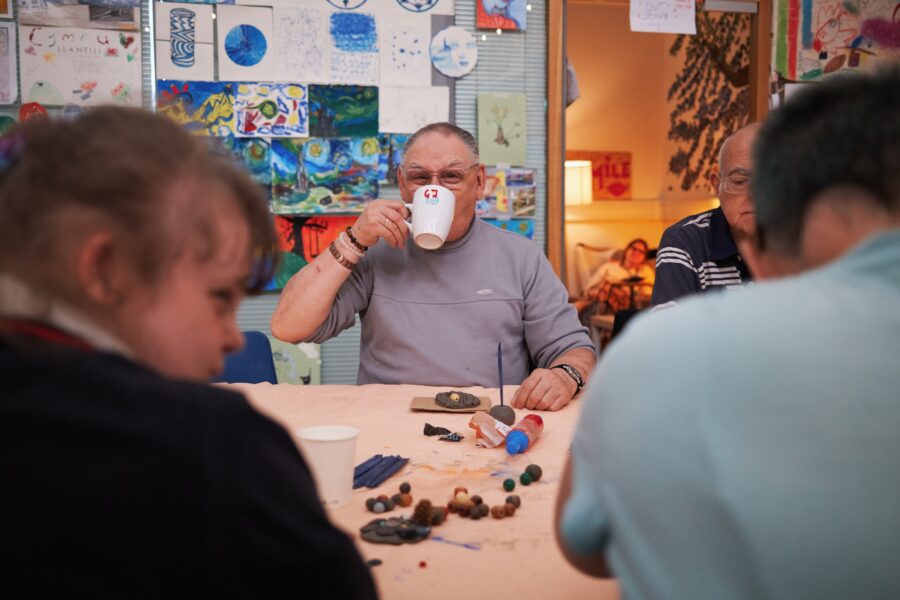 Man in a community centre drinking a cup of tea