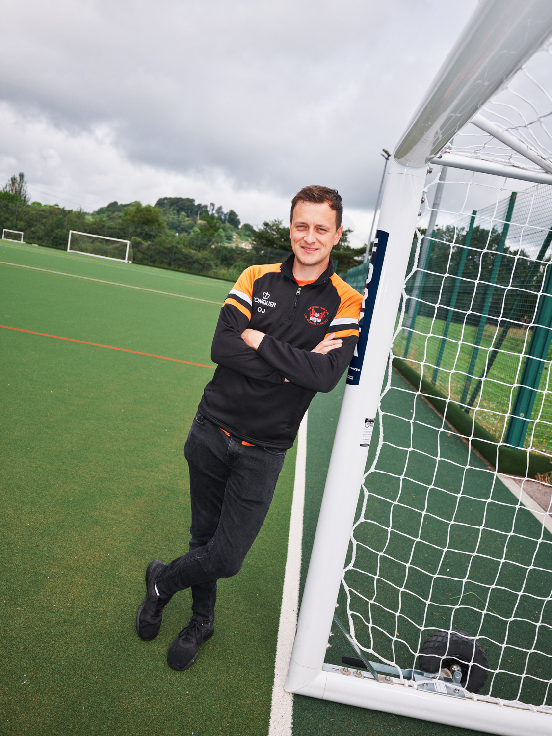 Football coach stood next to goalposts