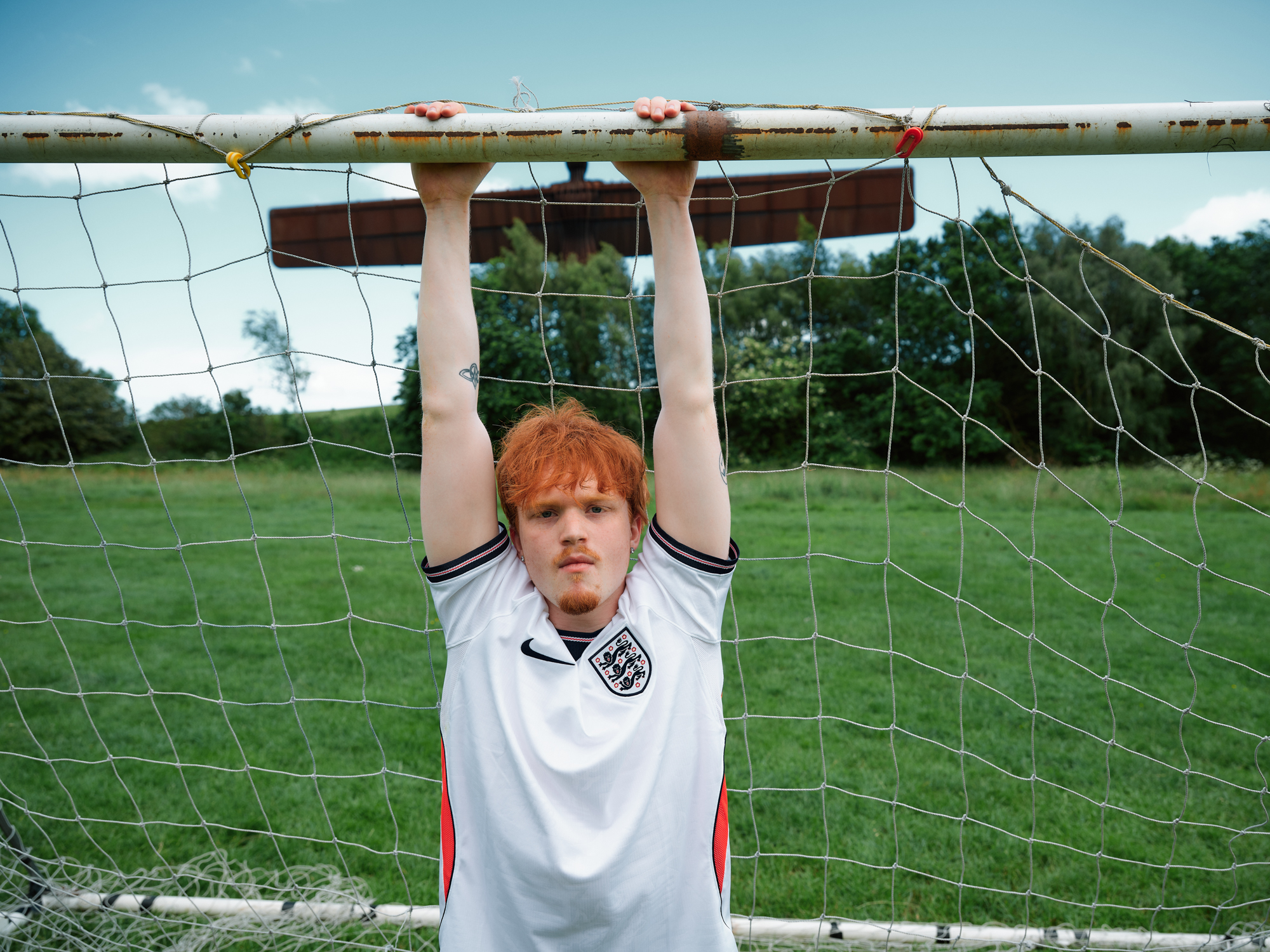 Man playing football hanging from goal crossbar