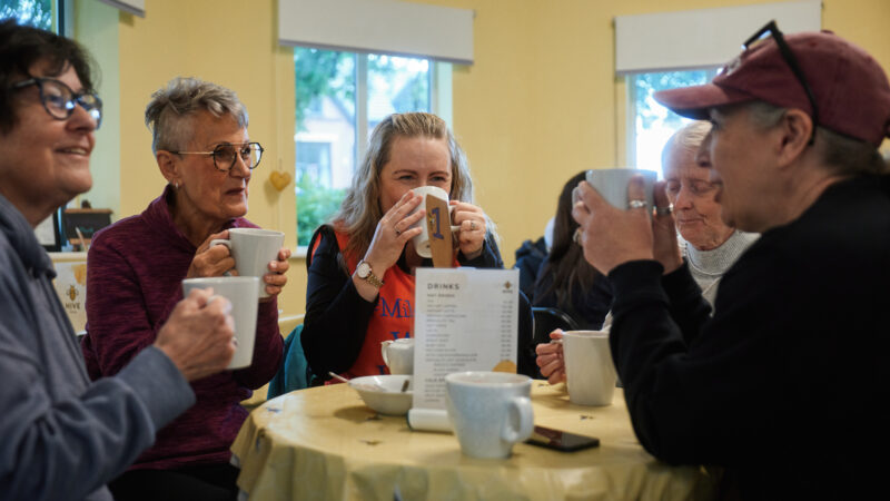 Group of 7 women around a table drinking tea and chatting