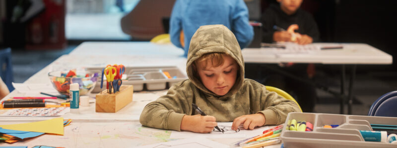 Young boy drawing with coloured pens on paper